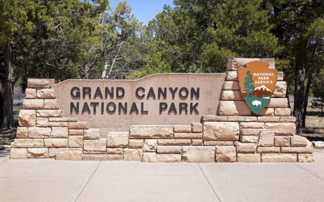 the entrance sign for the Grand Canyon National Park in bright sunlight