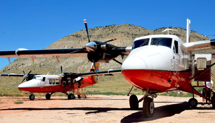 two sightseeing airplanes sitting at the Grand Canyon with desert scenery in the background