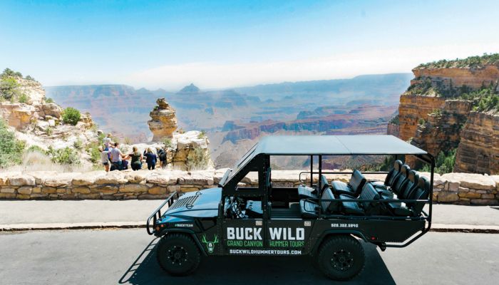 an open-air customized hummer vehicle parked at a Grand Canyon South Rim lookout point
