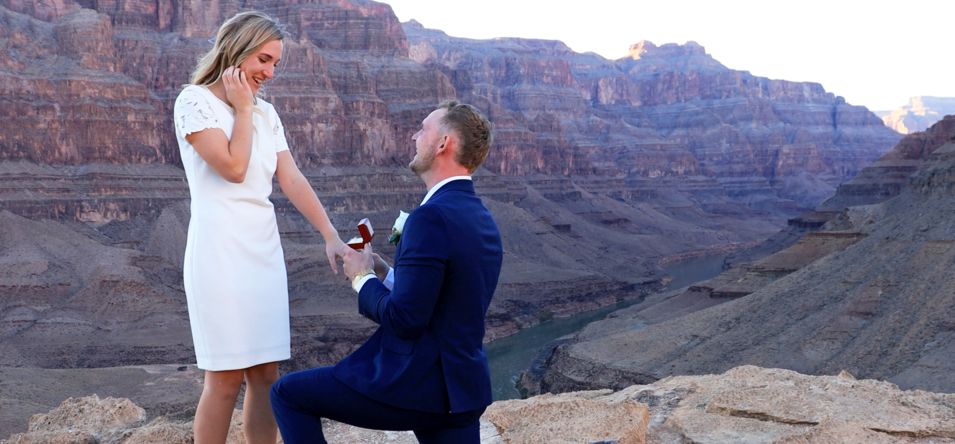 a man kneels while proposing to a woman at the Grand Canyon