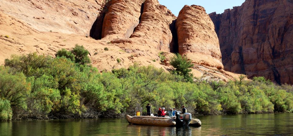 tourists floating down the colorado river near the canyon wall