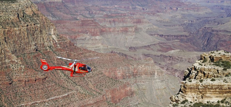 red helicopter flying over grand canyon national park