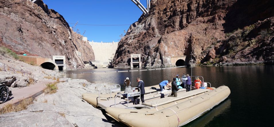 rafting boat on the colorado river with hoover dam in the background