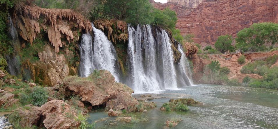 a canyon within Havasu Falls featuring large waterfalls and lined by greenery