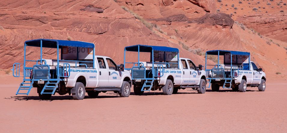three white trucks waiting to transport passengers to a lower antelope canyon tour