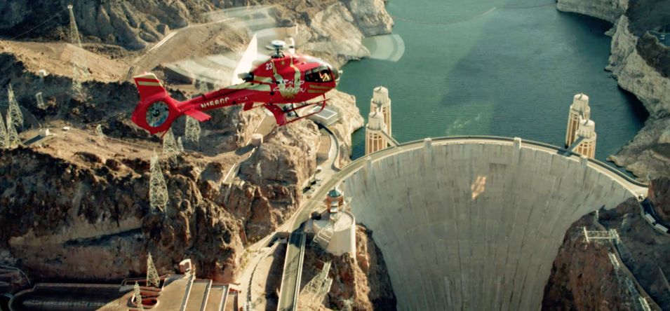 red helicopter flying over Lake Mead and Hoover Dam