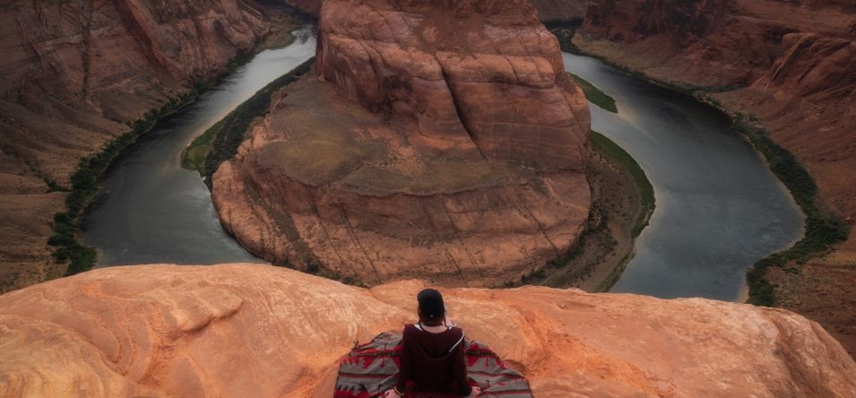 Person sitting at the edge at Page Arizona Horseshoe Bend.