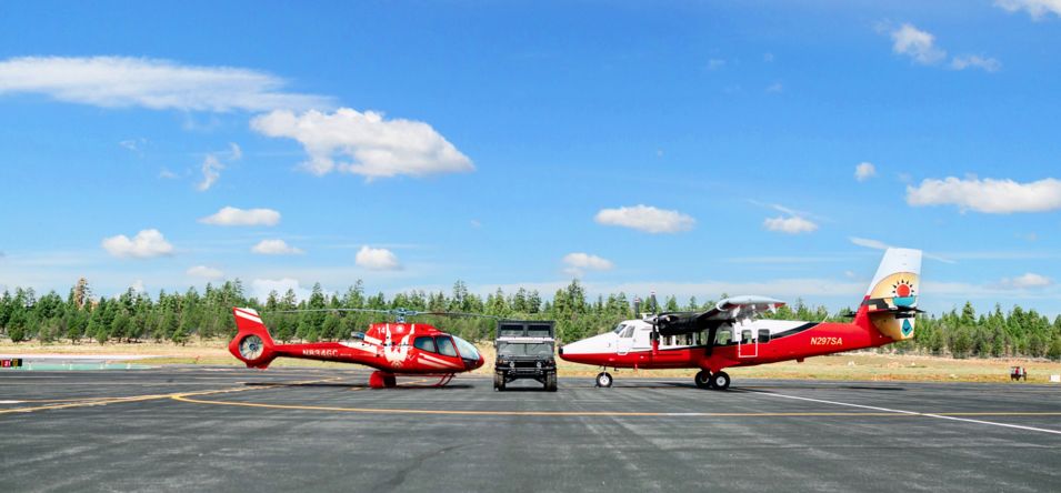 A helicopter, Hummer vehicle, and a sightseeing airplane displayed on Papillon's tarmac
