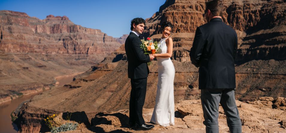 a couple stands on a plateau at the bottom of the Grand Canyon during a wedding ceremony