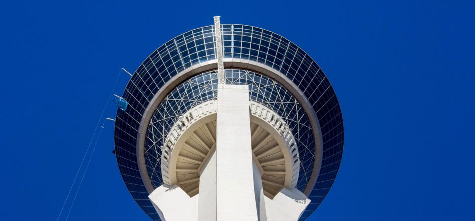 the STRAT Tower in Las Vegas, seen from below towering into the blue sky