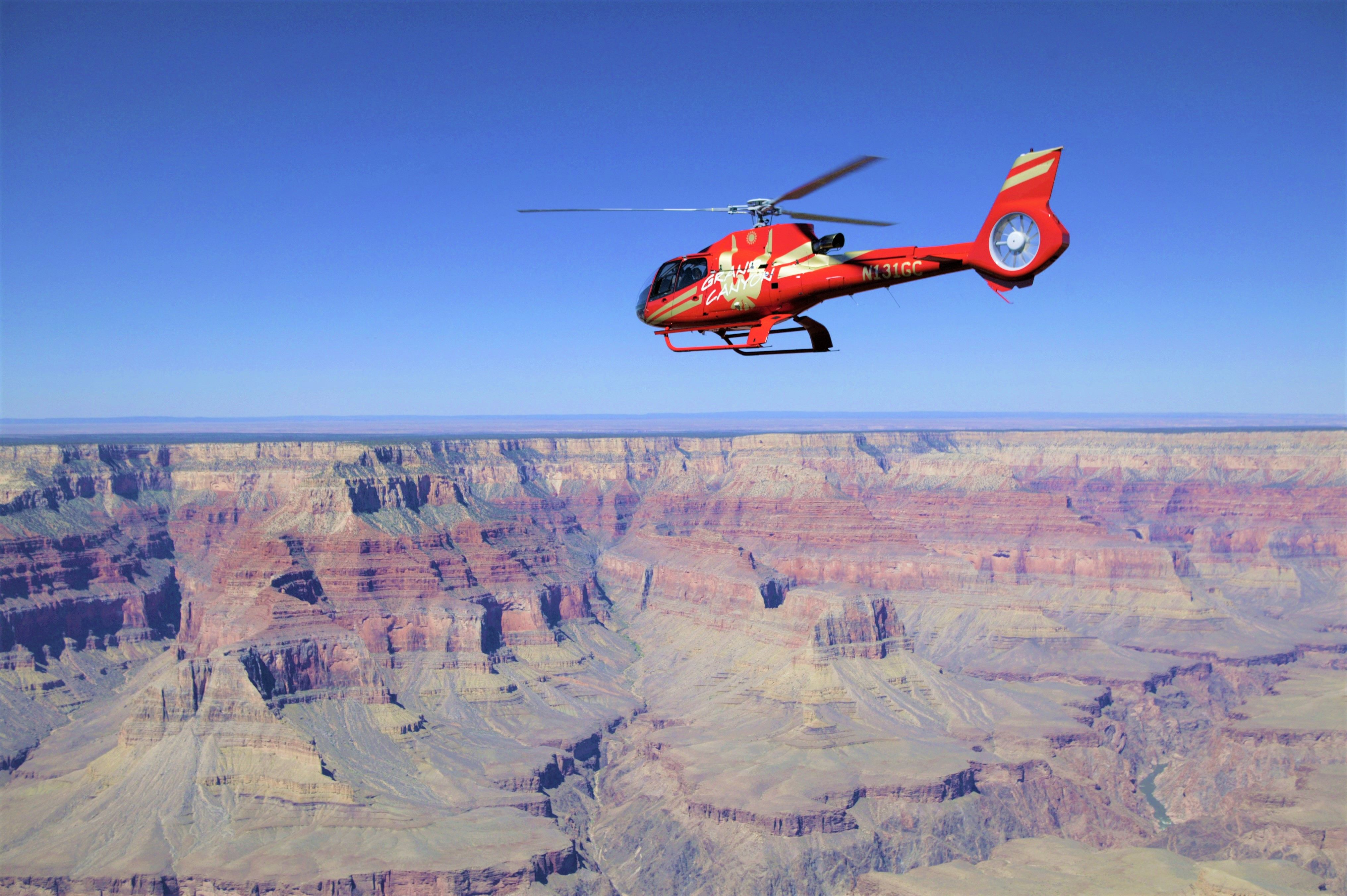 A red helicopter flies over a Grand Canyon National Park landscape
