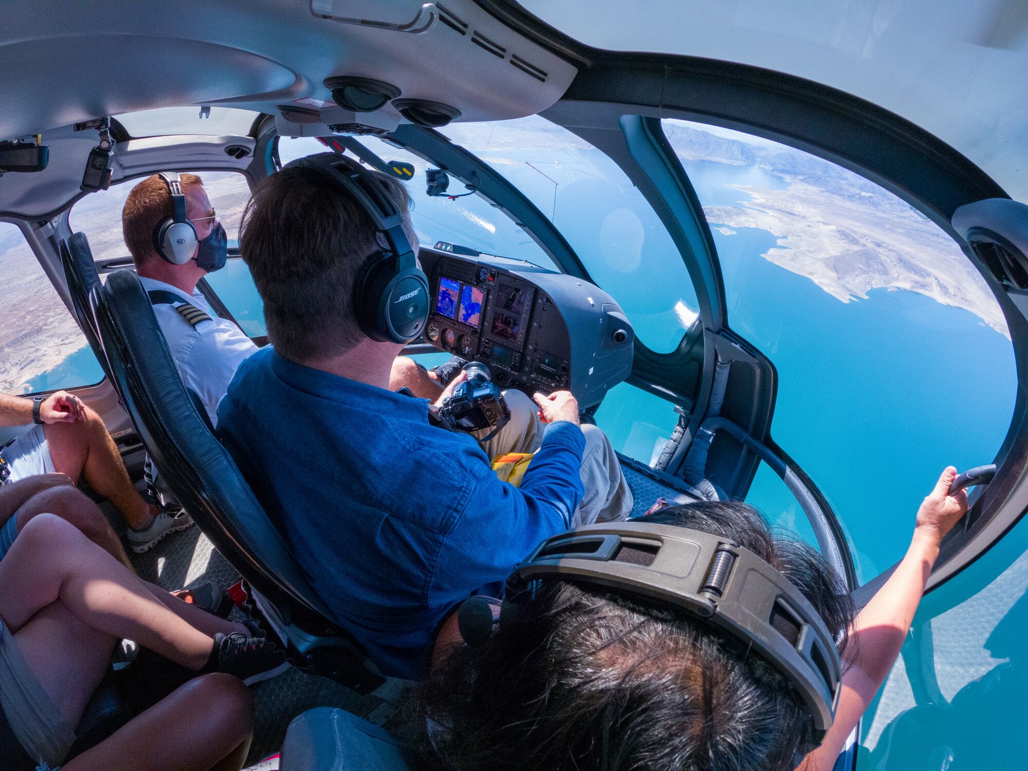 Two pilots seen from the inside of a touring helicopter while flying over Lake Mead