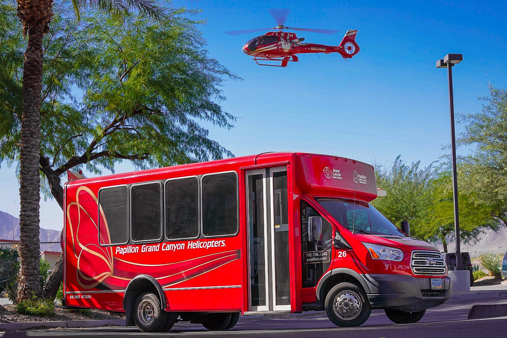 A Red Papillon shuttle vehicle viewed from the side with its company name and logo displayed