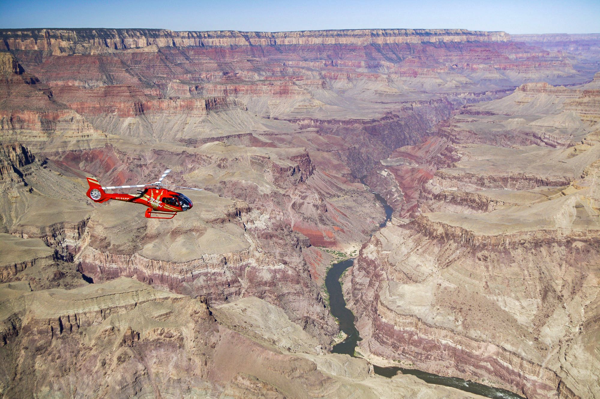 A helicopter tour flies over a massive stone gorge at the Grand Canyon National Park