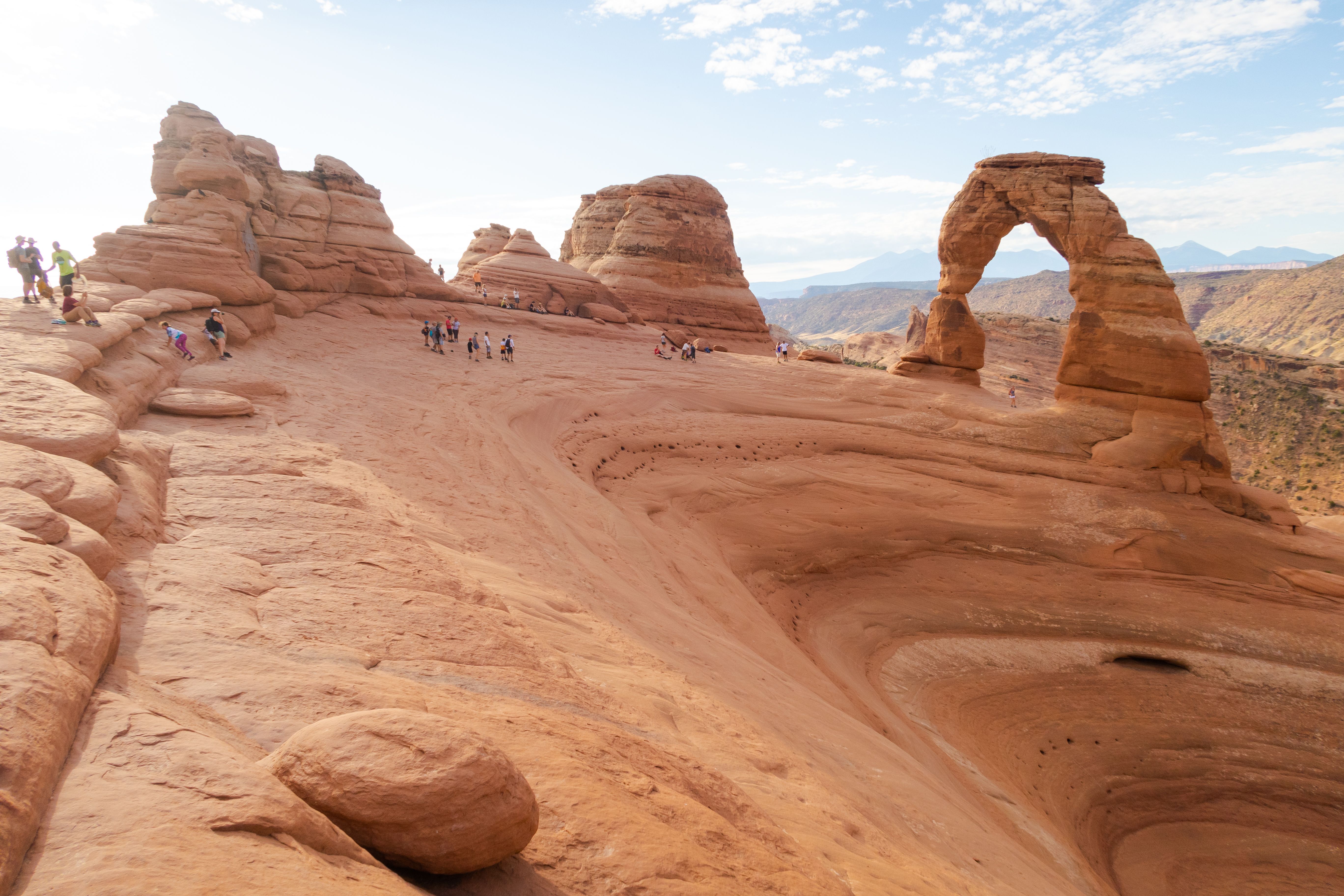 Visitors gather at an enormous arch-shaped rock formation within Arches National Park