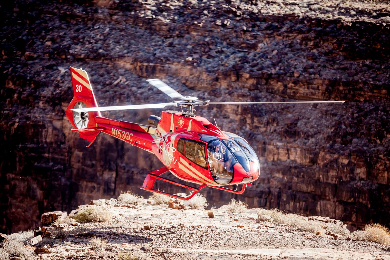 An Ecostar helicopter flies through the ancient stone walls of the Grand Canyon